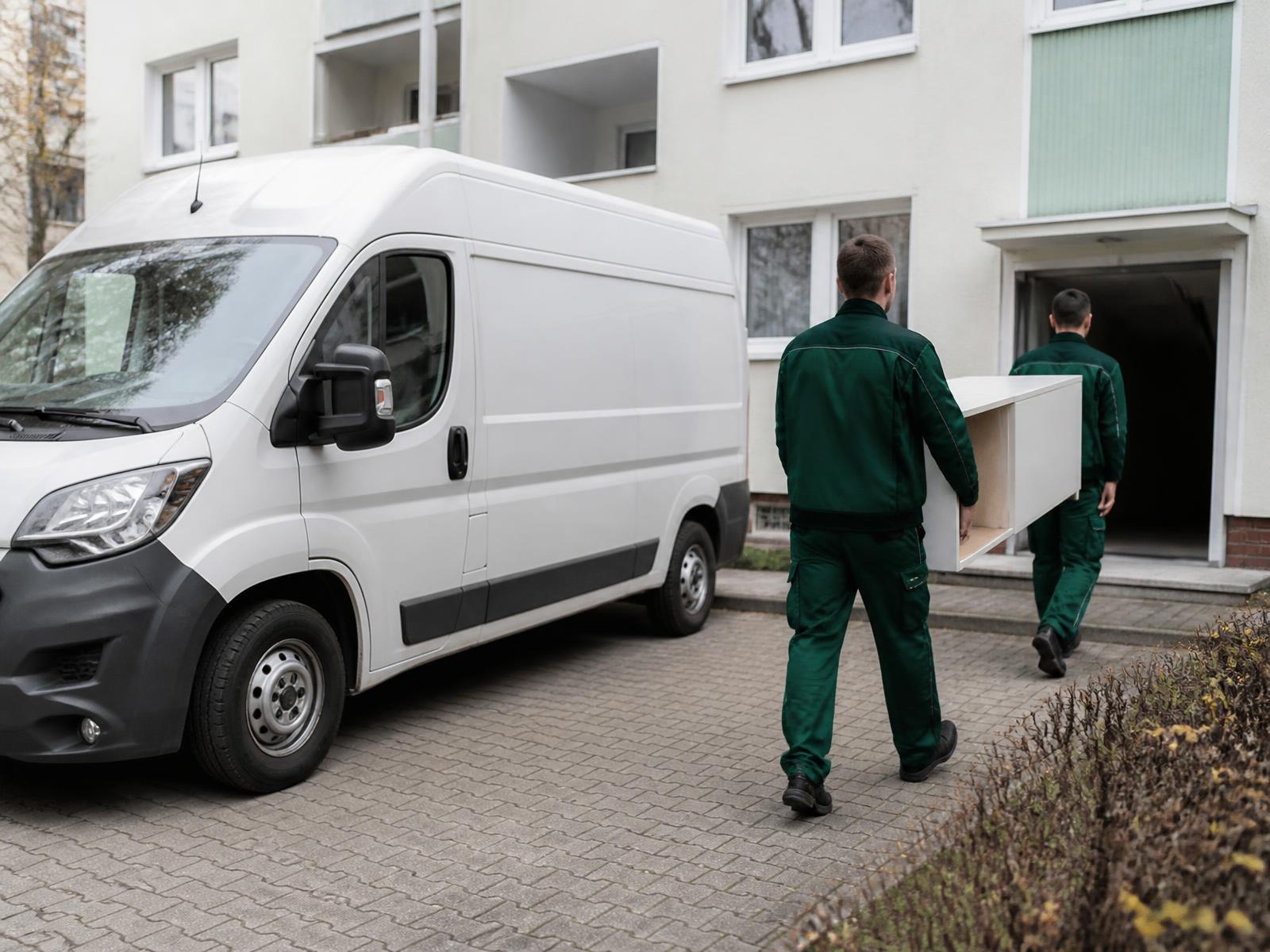 Mitarbeiter von MER tragen Möbel zu einem sauberen Transporter vor einem Wohnhaus